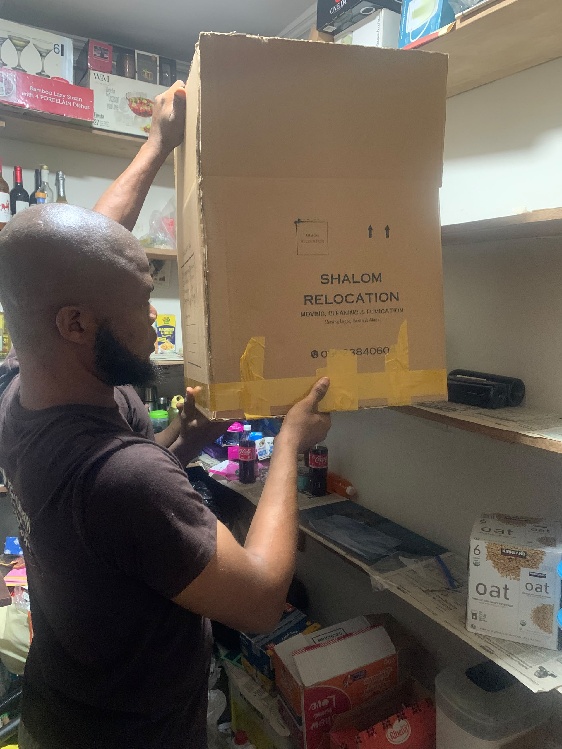 A mover placing a packed Shalom Relocation box with household belongings.