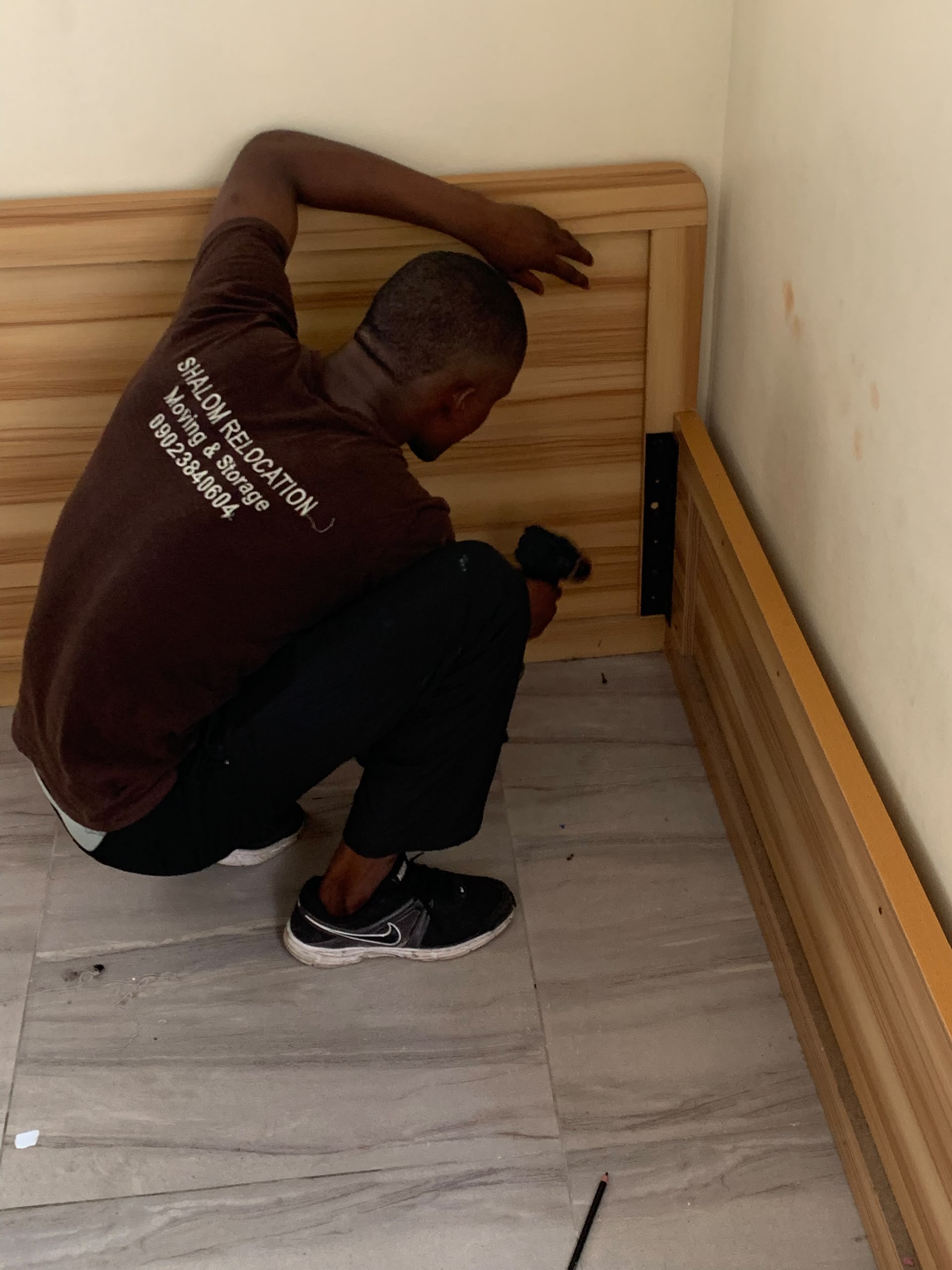 A mover working on a wooden furniture frame before it is moved.