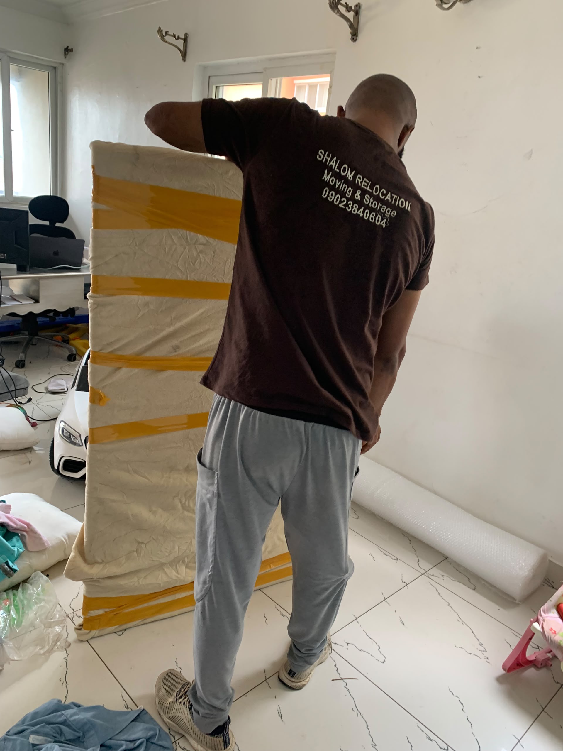 A team member securing protective wrapping around a large household item.