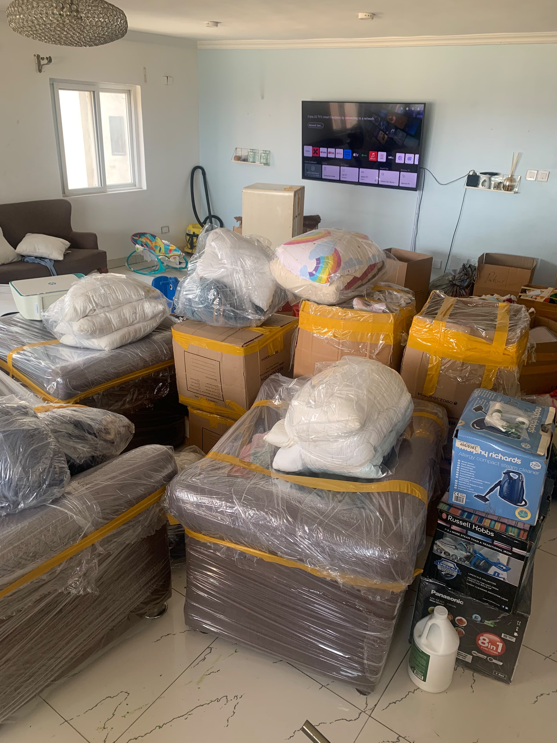Wrapped furniture, labelled boxes and household belongings gathered inside a home.