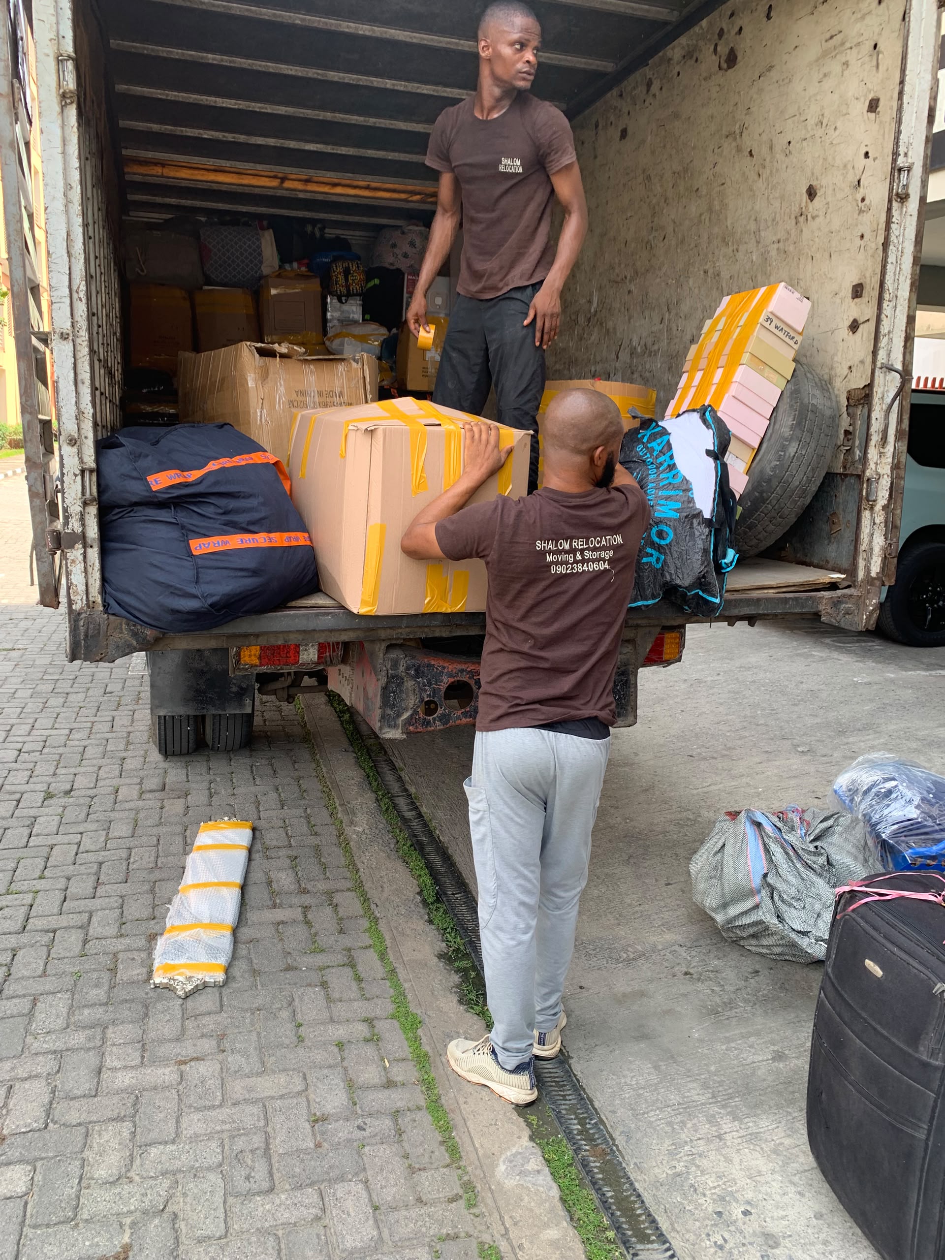 Two team members loading a packed box into a truck with other belongings.